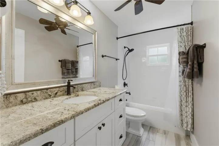 Bathroom featuring a white vanity with a light granite countertop, an undermount sink, and a dark bronze faucet
