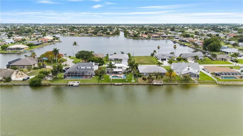 Waterfront property featuring direct canal access, an attached private dock, and a screened-in pool enclosure