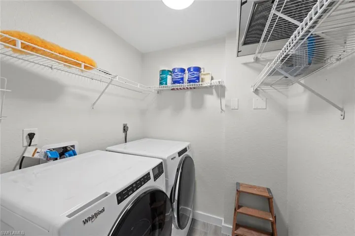 Laundry room with a textured wall, wood finished floors, and washer and clothes dryer