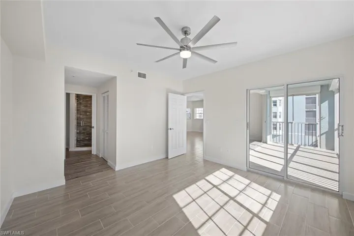 Unfurnished bedroom featuring wood finish floors, access to exterior, and a ceiling fan