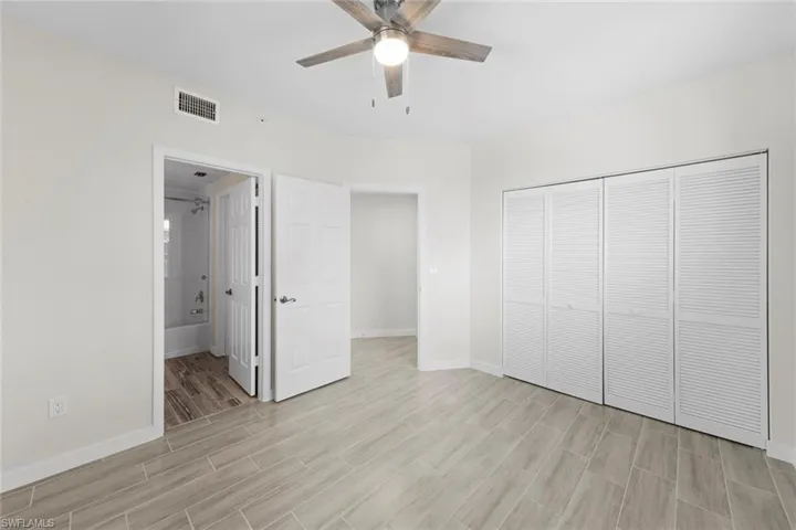 Unfurnished bedroom featuring wood finish floors, a closet, a ceiling fan, and connected bathroom