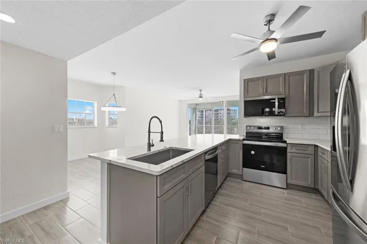 Kitchen with stainless steel appliances, a peninsula, wood finish floors, backsplash, and healthy amount of natural light