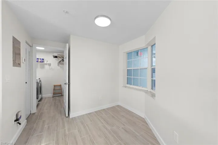 Unfurnished bedroom with a closet, electric panel, washing machine and clothes dryer, and wood tiled floors