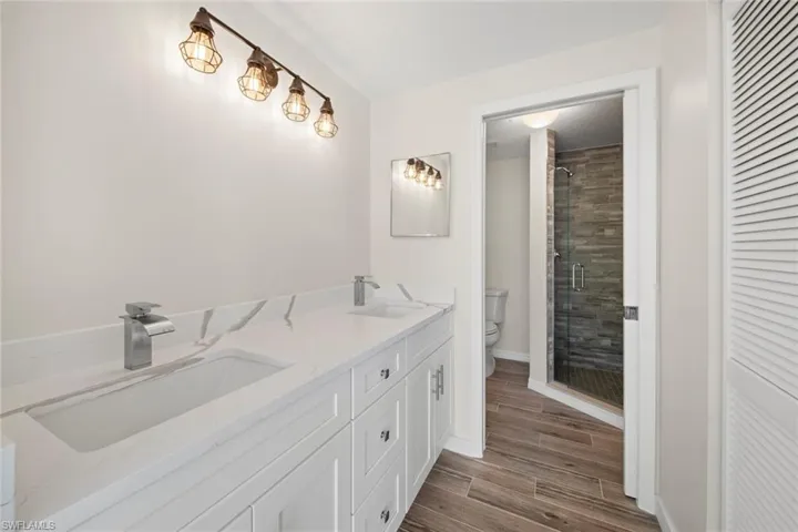Full bath with double vanity, wood tiled floors, a stall shower, and a closet