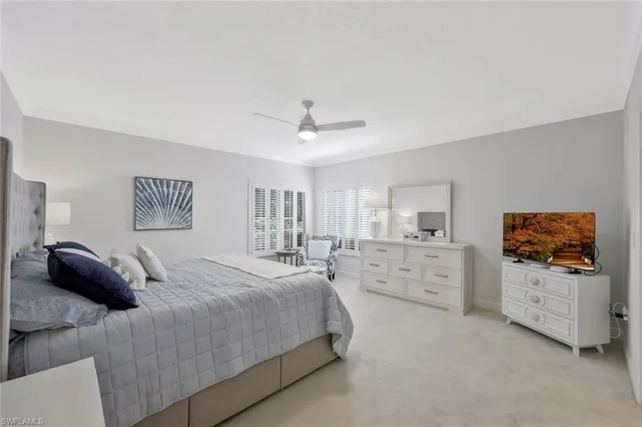 Bedroom featuring light colored carpet, ornamental molding, and ceiling fan