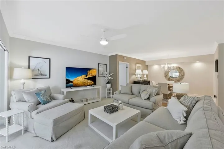 Living room featuring a ceiling fan, a chandelier, and ornamental molding