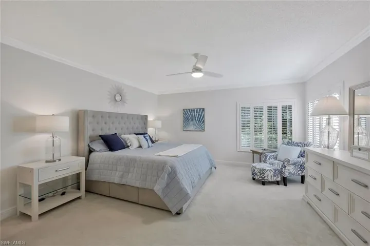 Bedroom with ornamental molding, light carpet, a ceiling fan, and a textured ceiling