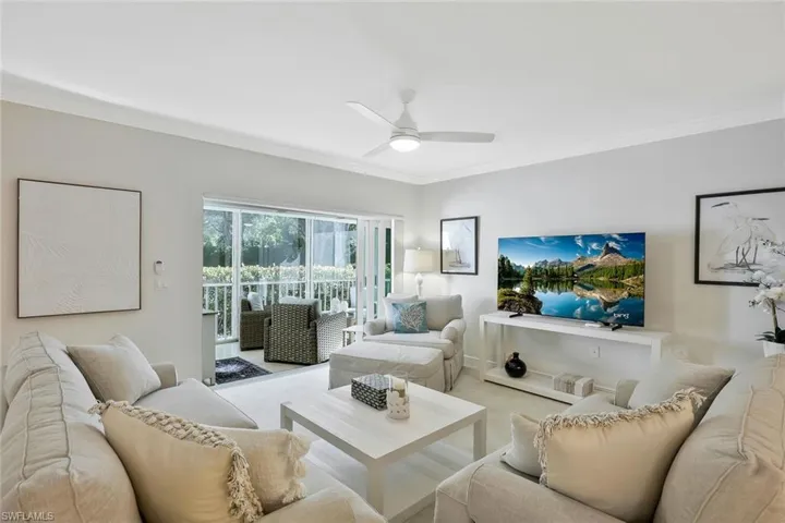 Living area with carpet floors, crown molding, and ceiling fan
