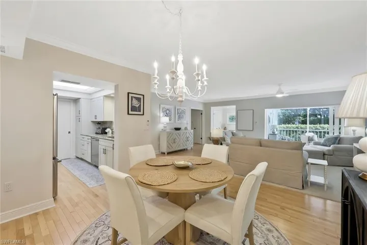 Dining area featuring light wood finished floors, a chandelier, crown molding, and a ceiling fan
