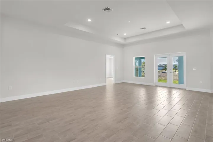 Spare room with recessed lighting, french doors, wood finish floors, and a tray ceiling