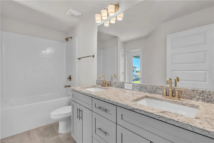 Full bath with double vanity, shower / bathtub combination, and wood finish floors