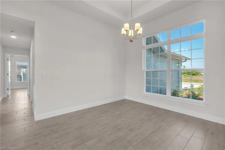 Unfurnished room with wood tiled floors, a chandelier, and healthy amount of natural light