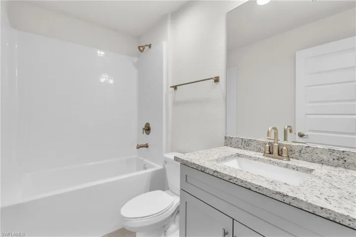 Bathroom featuring vanity, bathing tub / shower combination, and a textured wall