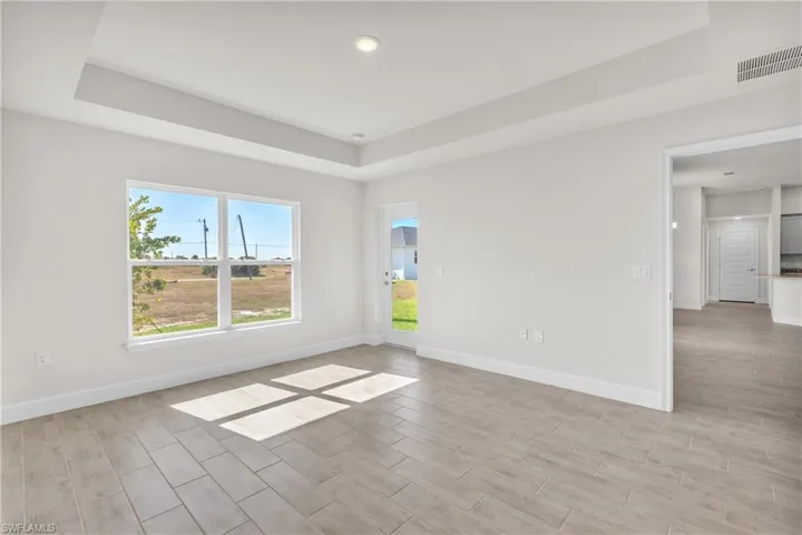 Unfurnished room featuring a raised ceiling and wood finish floors
