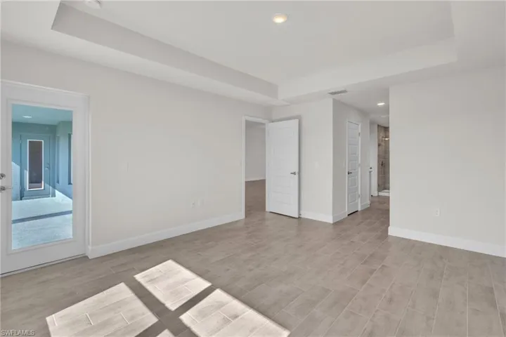 Empty room with a tray ceiling, wood tiled floors, and recessed lighting