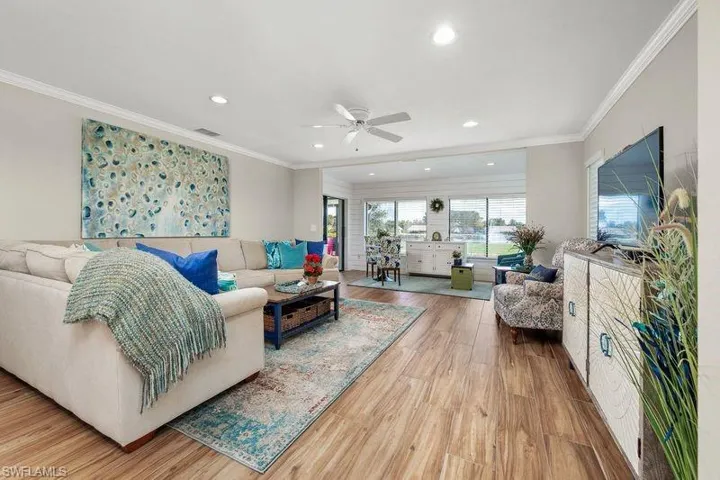 Living room featuring wood-type flooring, ceiling fan, and crown molding