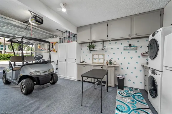 Garage featuring a garage door opener, stacked washer and dryer, and ceiling fan