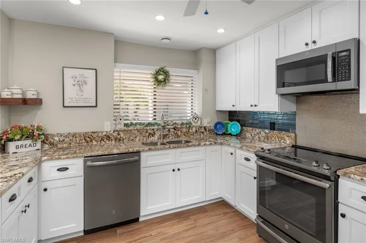 Kitchen with appliances with stainless steel finishes, sink, and white cabinets