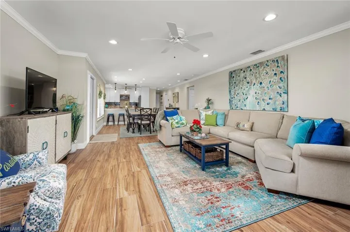 Living room with ceiling fan, hardwood / wood-style flooring, and ornamental molding
