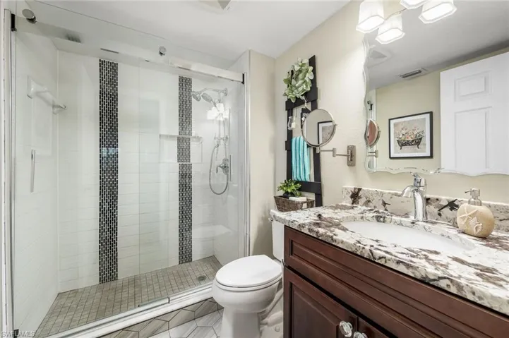 Bathroom with vanity, a shower with shower door, toilet, and tile patterned floors