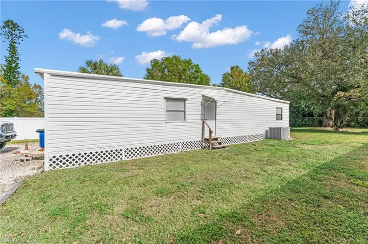View of home's exterior with cooling unit and a yard