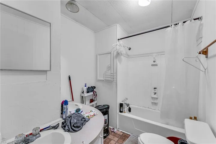 Full bathroom with vanity, a textured ceiling, shower / bath combo, and toilet