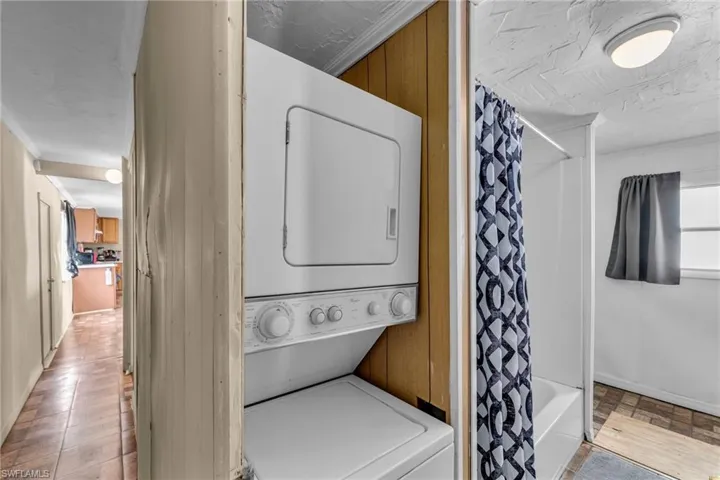 Laundry area with stacked washing maching and dryer and light wood-type flooring