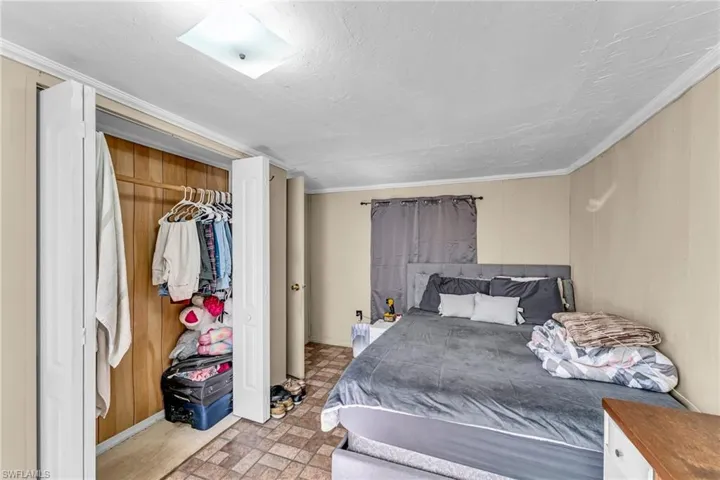 Bedroom with crown molding, a textured ceiling, wooden walls, and a closet