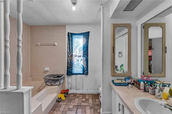 Bathroom featuring vanity, toilet, and a tub