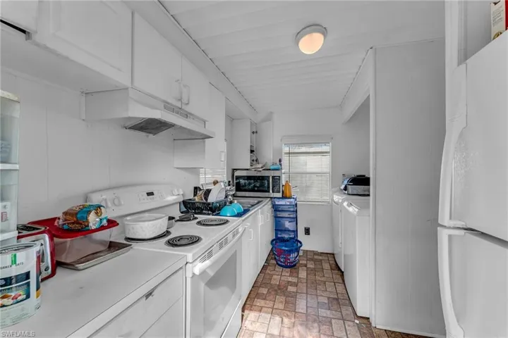 Kitchen with white cabinetry, washing machine and dryer, and white appliances