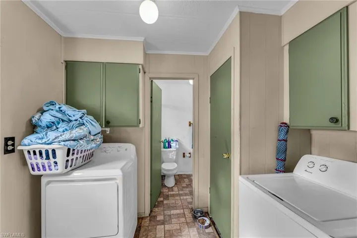 Washroom featuring cabinets, crown molding, and washer and dryer