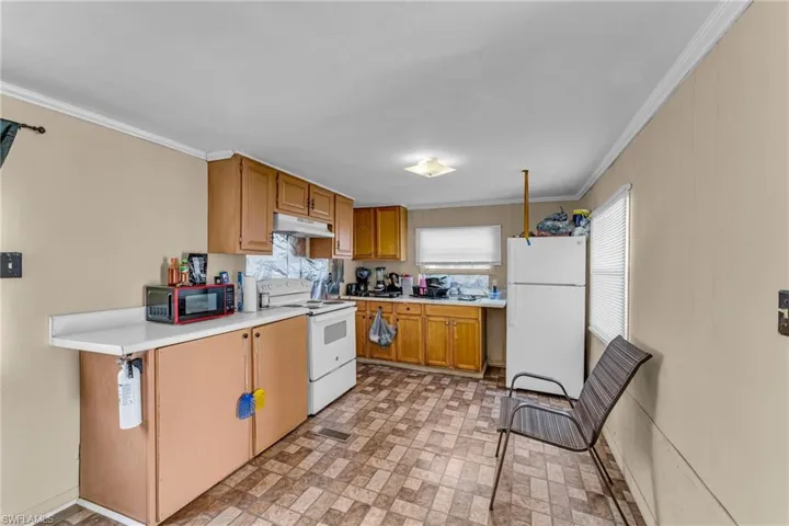 Kitchen with crown molding, white appliances, and sink