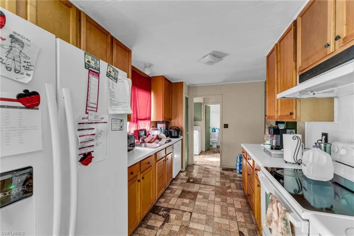 Kitchen with white appliances, washer / dryer, and sink