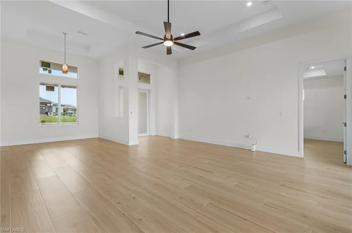 Unfurnished room featuring a raised ceiling, light hardwood / wood-style flooring, and ceiling fan