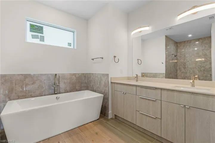 Bathroom featuring a bathing tub and double vanity