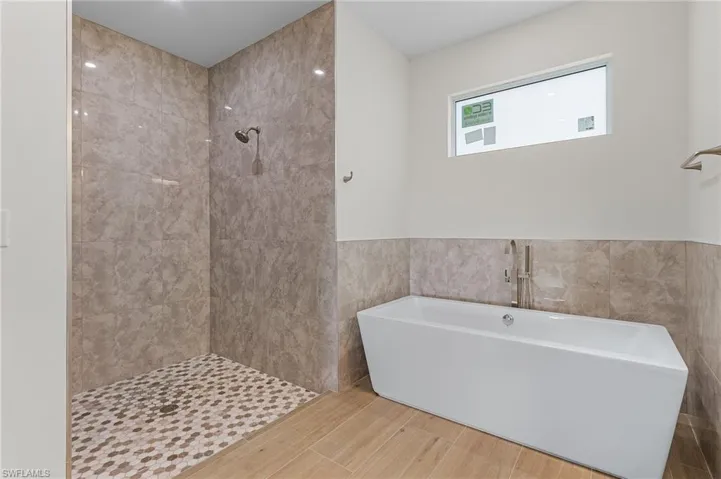 Bathroom with tile walls and shower with separate bathtub