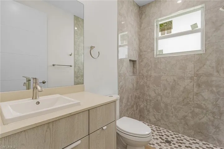 Bathroom with vanity, toilet, and a tile shower