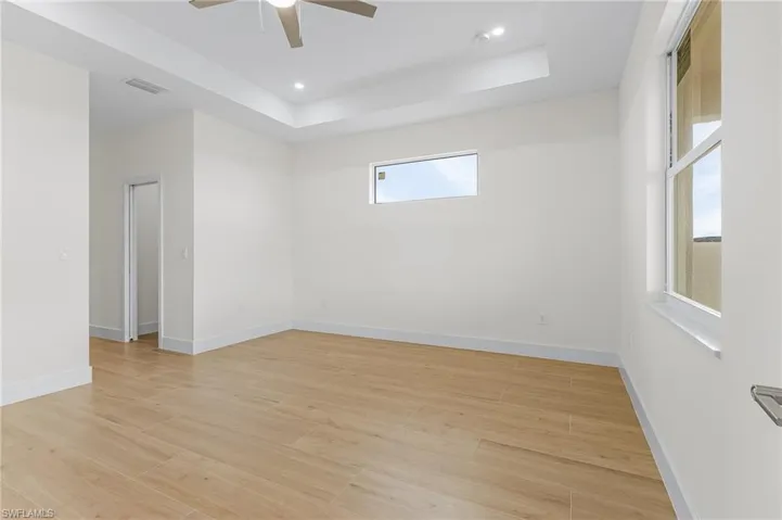 Unfurnished room featuring a tray ceiling, light hardwood / wood-style flooring, and ceiling fan