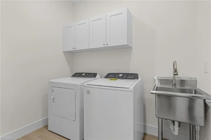 Clothes washing area with sink, cabinets, independent washer and dryer, and light wood-type flooring