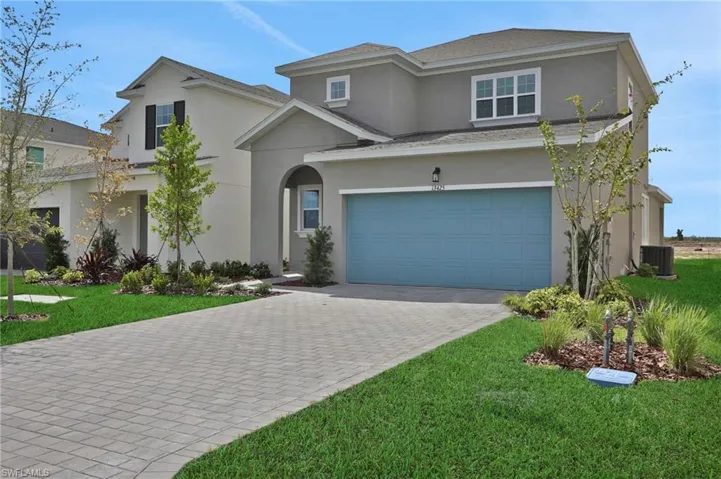 View of front of property with a garage, a front yard, stucco siding, and driveway