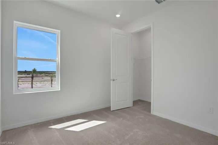 Unfurnished bedroom featuring light carpet and a spacious closet