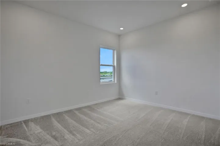Empty room with light colored carpet and recessed lighting