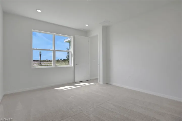 Empty room with light carpet and recessed lighting