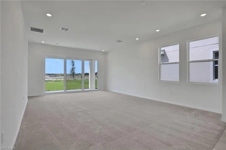 Empty room with recessed lighting and light colored carpet