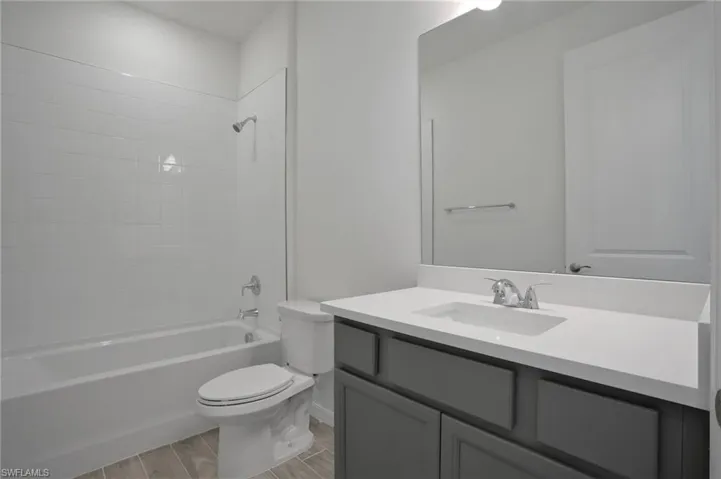 Bathroom with vanity, washtub / shower combination, and wood tiled floors