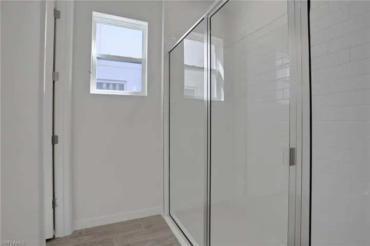 Bathroom featuring a shower stall and wood tiled floors