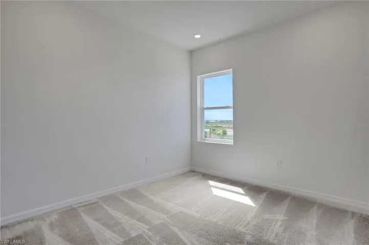 Empty room with light carpet and recessed lighting
