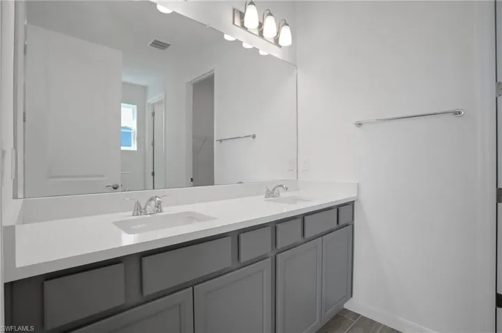 Bathroom with double vanity and baseboards