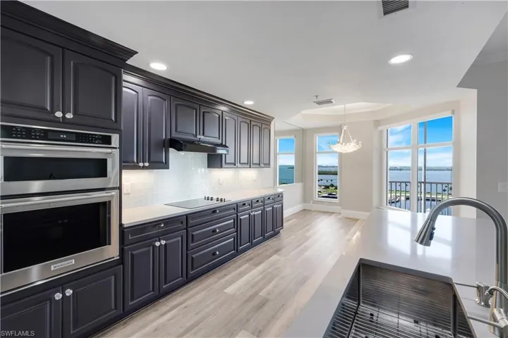 Kitchen featuring dark wood cabinetry, light countertops, built-in stainless steel double ovens, and a tile backsplash