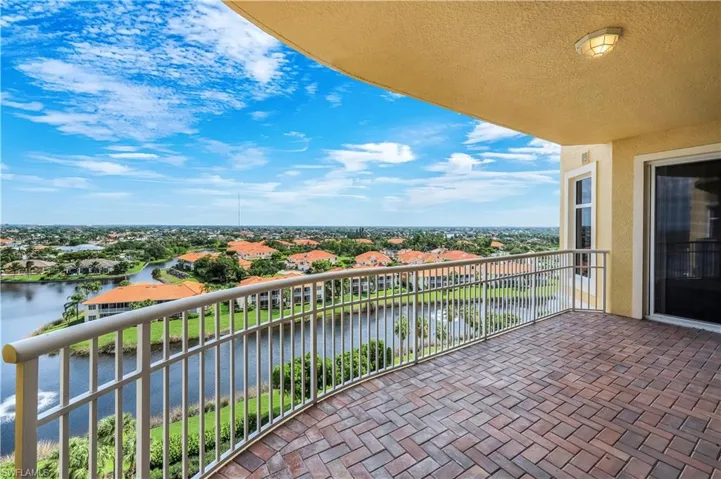 Expansive front, curved balcony featuring fountain and neighborhood views, brick paver flooring and sliding glass doors leading into BR2, Den, and BR3